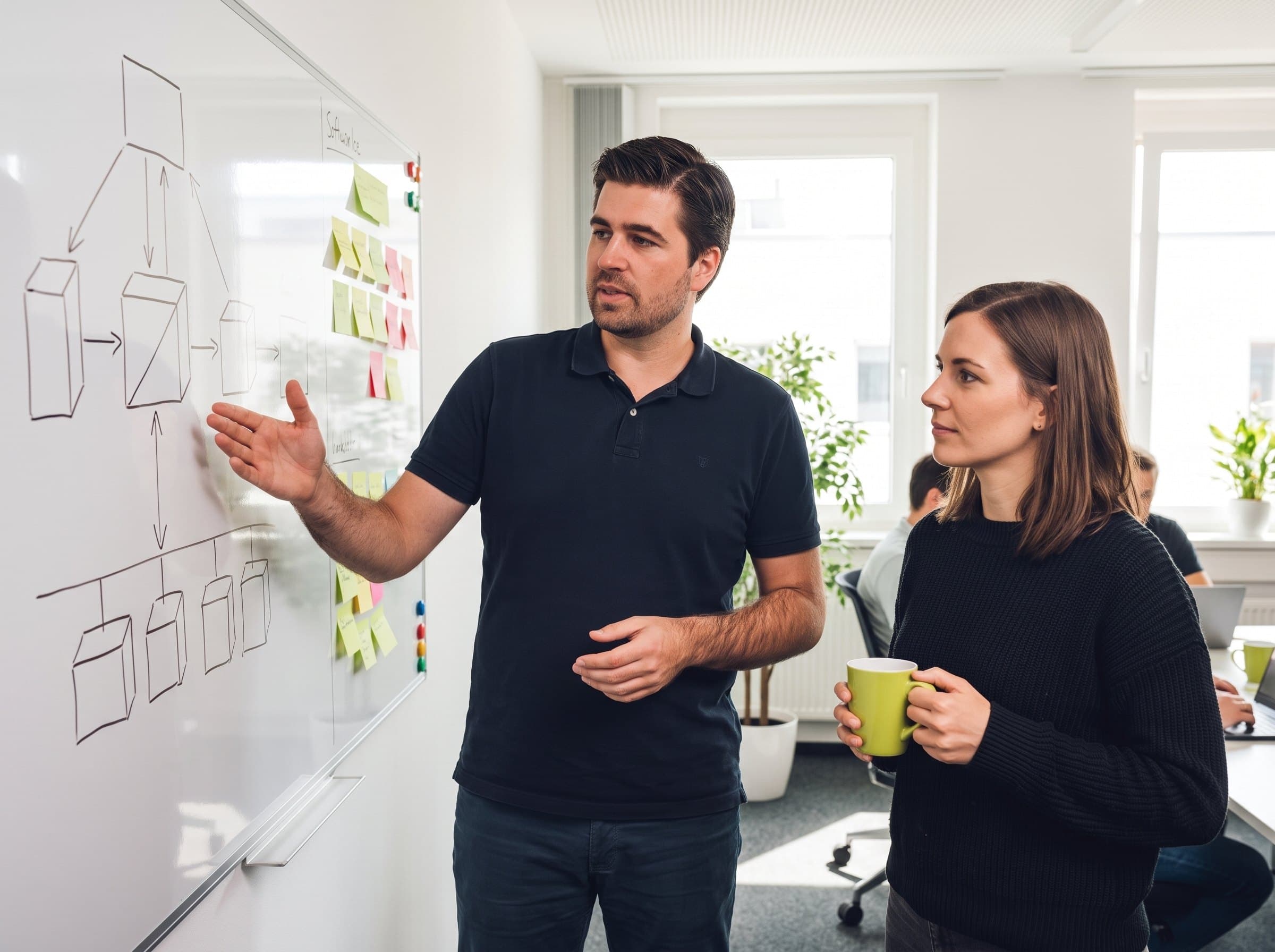 Alexander Gassner explaining a process to a client at a whiteboard
